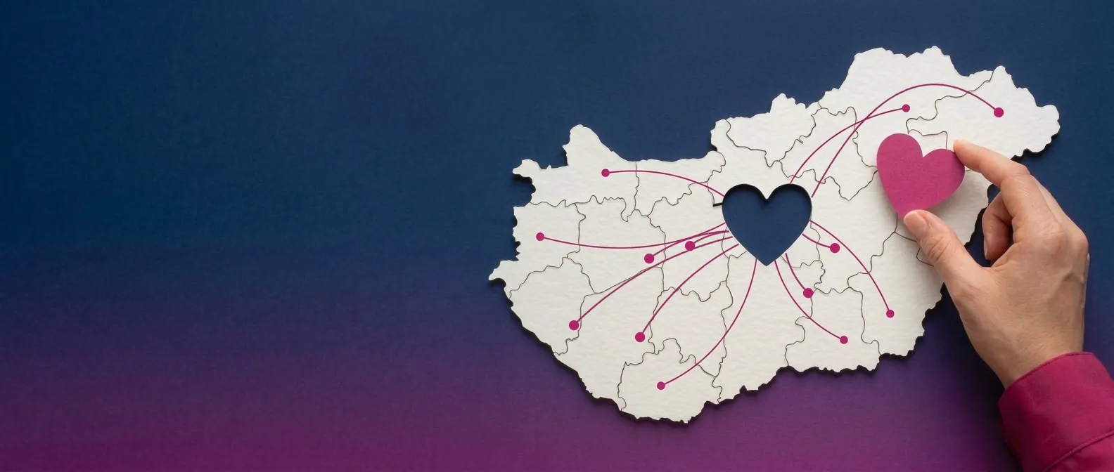 Magyarország alakú fehér puzzle szív alakú hiányzó darabbal, belőle magenta vonalak futnak szét az ország minden irányába; egy kéz illeszti be a magenta szívet